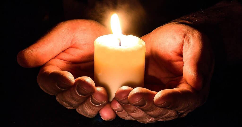 hands holding a candle with dark background