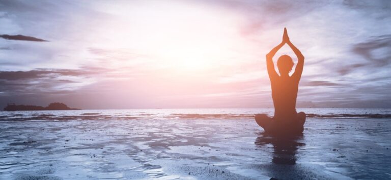 Woman doing seated yoga on a beach
