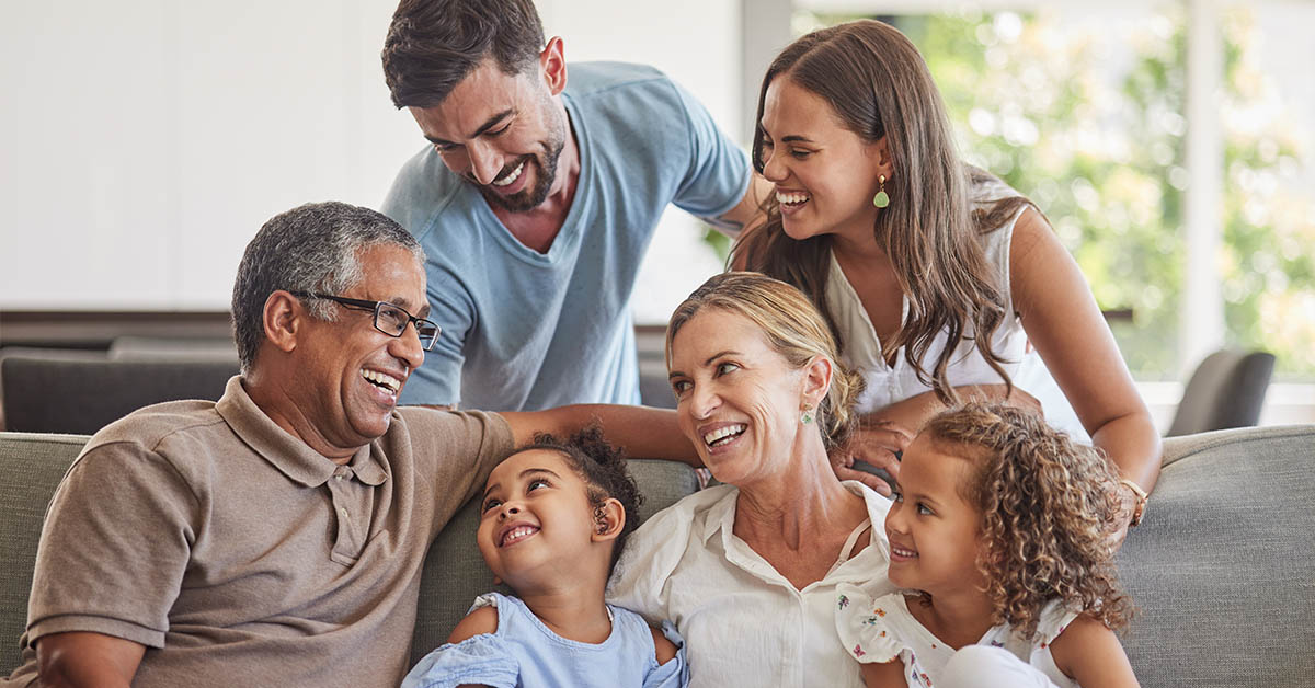 A joyful family gathering, featuring adults and children laughing together on a couch in a bright, cozy living room.