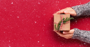 hands holding a gift with a red background and snowflakes