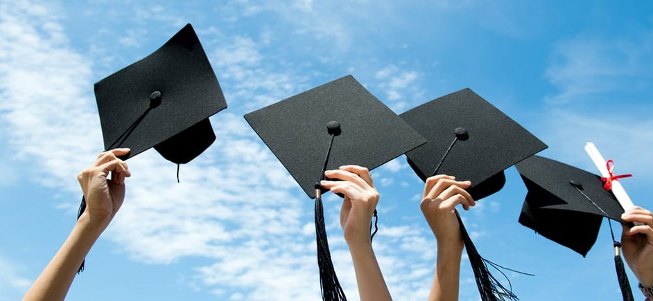 Graduation hats held up to sky