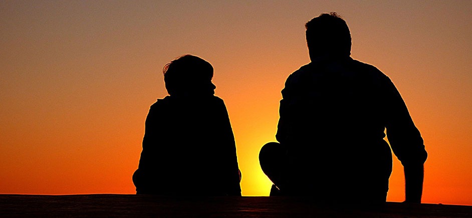 Silhouette of father and son talking in the sunset