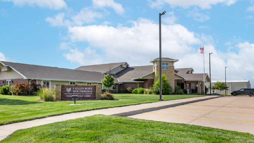 A building with a sign for "Valley Hope Moundridge" is shown, surrounded by green grass and trees under a blue sky.