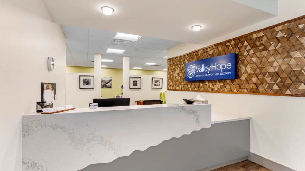 A modern reception area featuring a marble counter, wooden wall decor, and a sign for "Valley Hope" with a welcoming atmosphere.